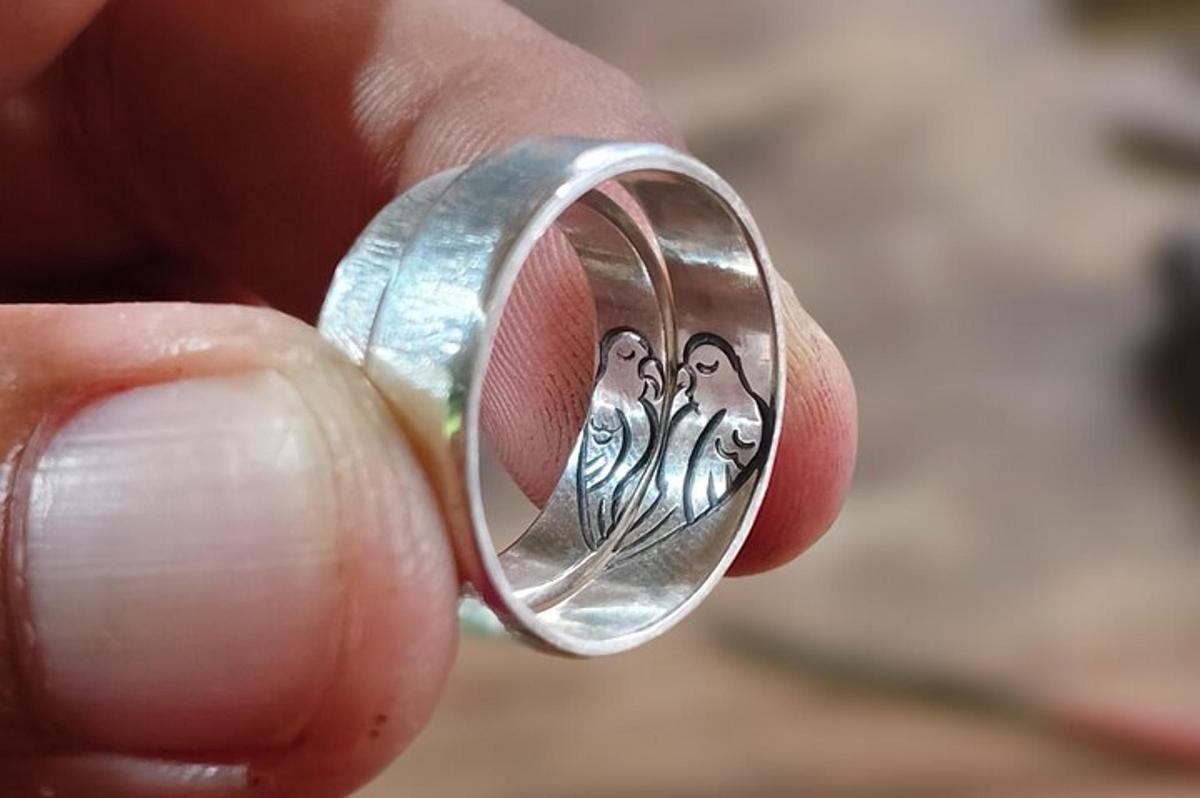 una mano che tiene un anello d'argento con una farfalla sopra