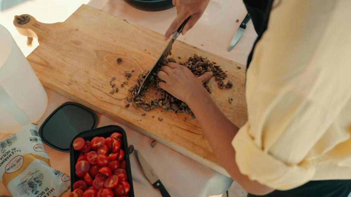 uma pessoa cortando frutas vermelhas em uma tábua de corte