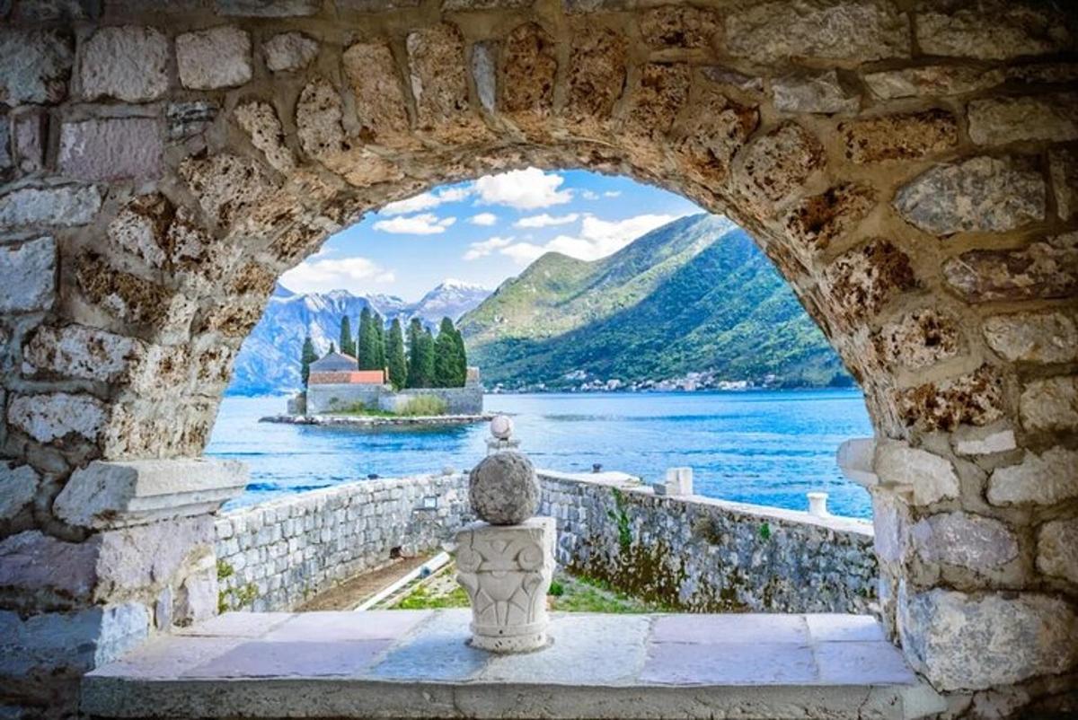 un arco in un muro di pietra con vista su un lago