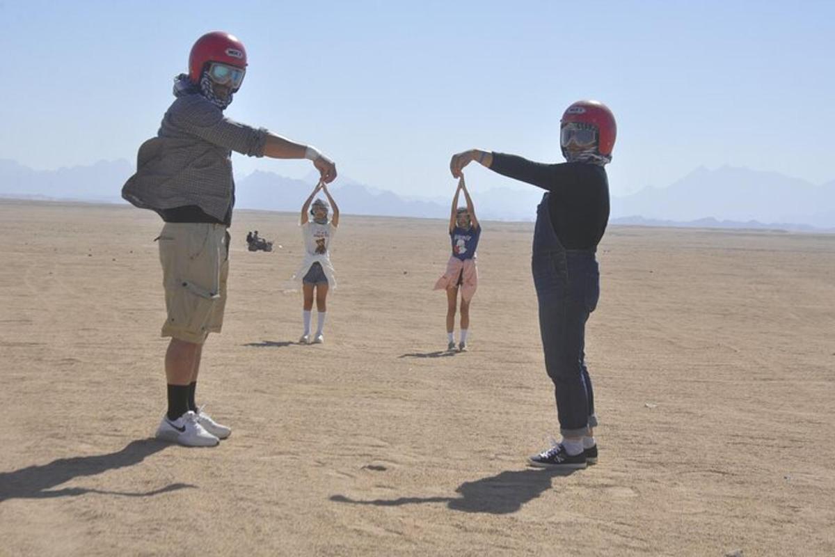 um grupo de pessoas no deserto brincando com uma pipa