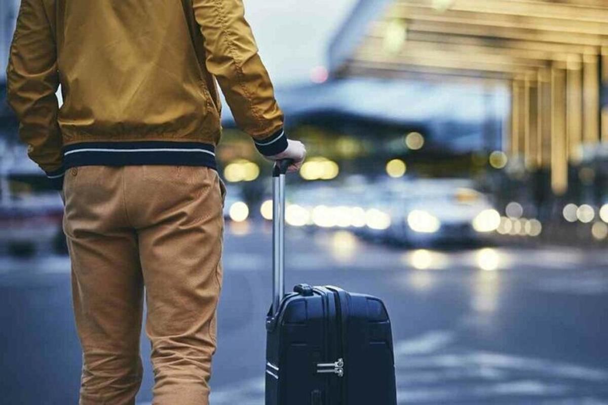一名男子提着行李箱站在街上