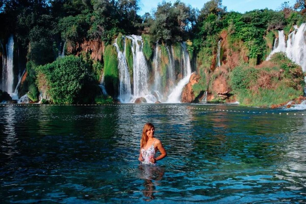 seorang wanita berdiri di dalam air di hadapan air terjun