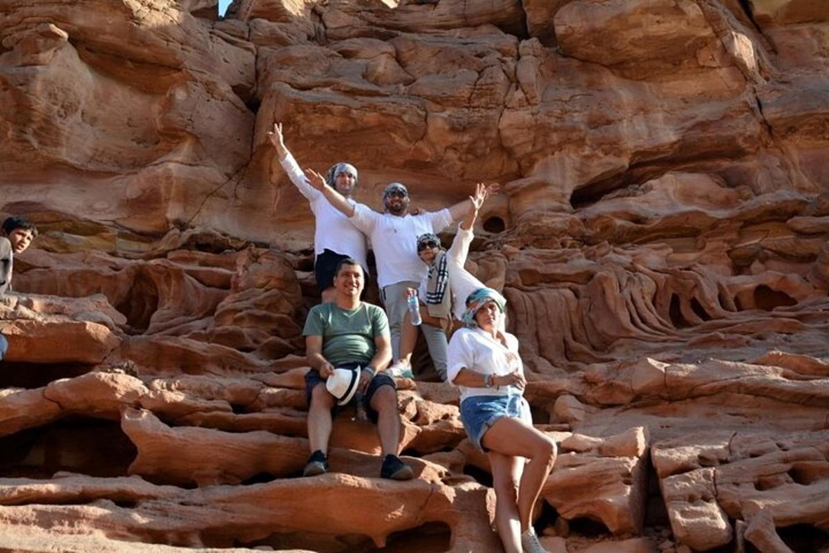 un gruppo di persone sedute sulle rocce di fronte a una scogliera