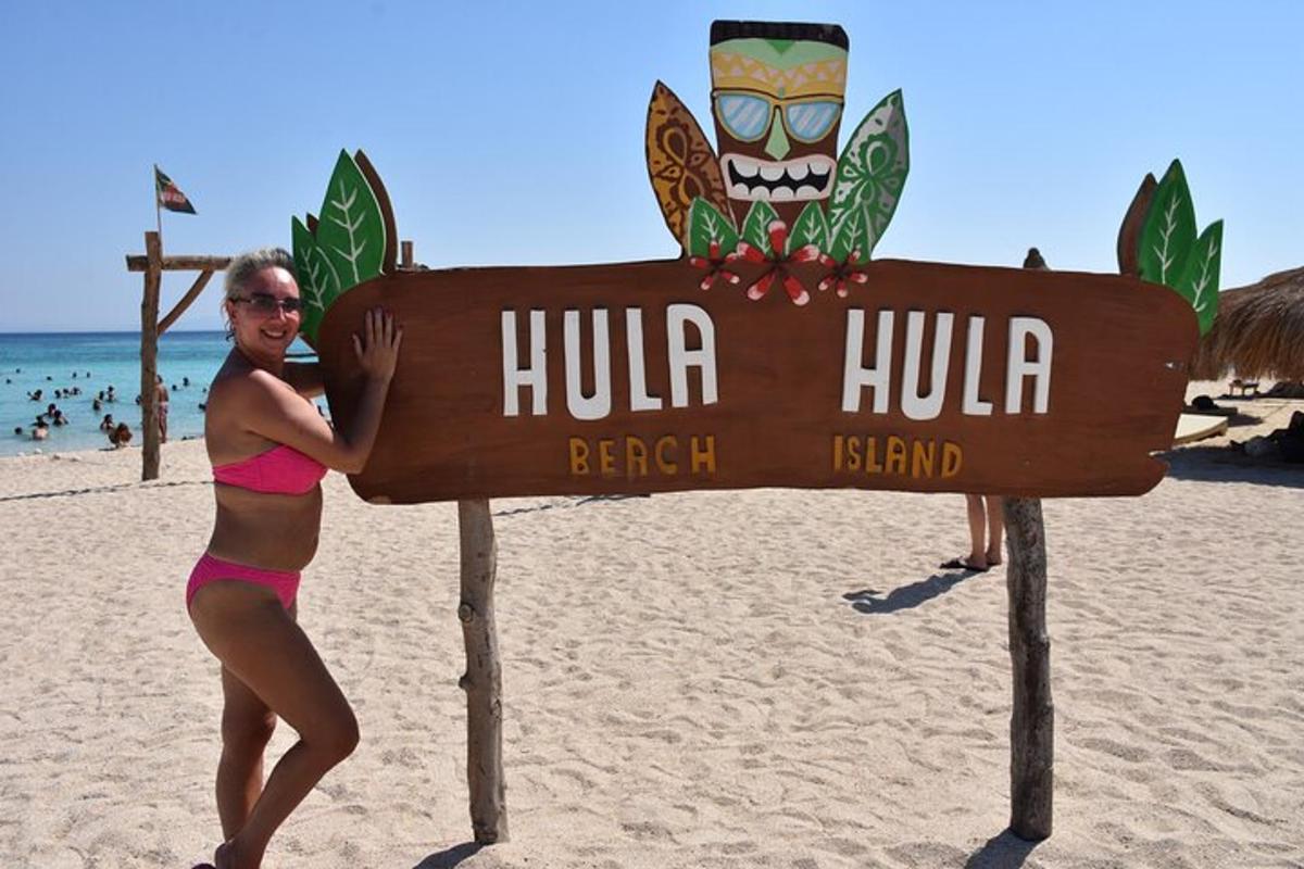 Una mujer en bikini parada junto a un cartel en la playa.