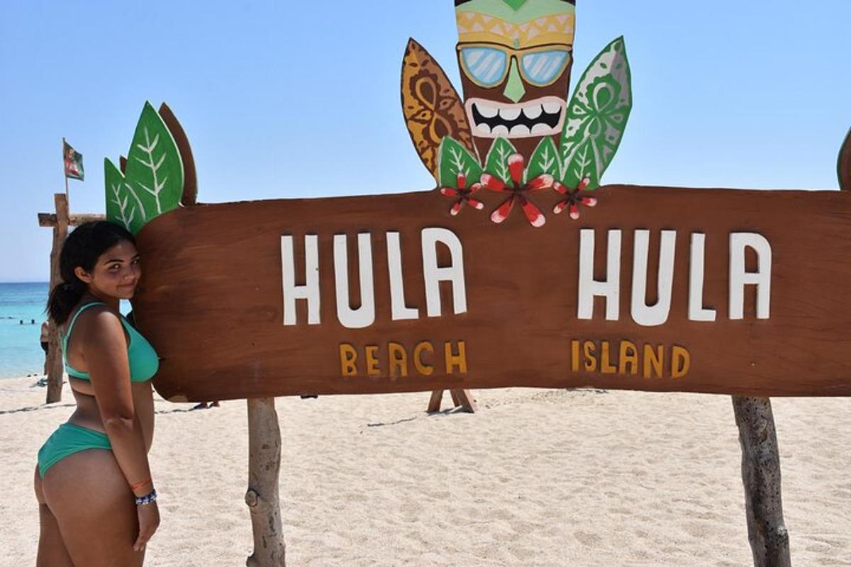 Una mujer parada junto a un cartel en la playa.