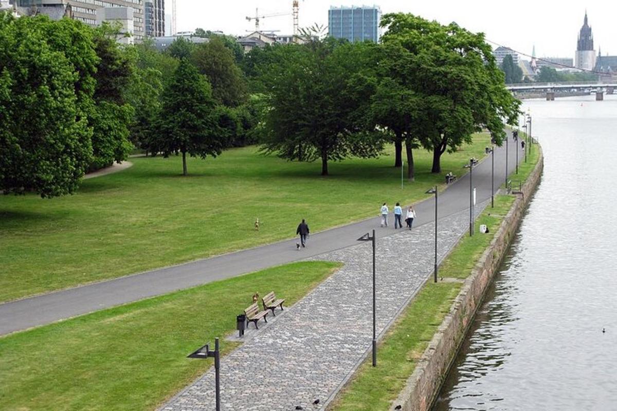 en park med folk som sitter på benker ved siden av en elv