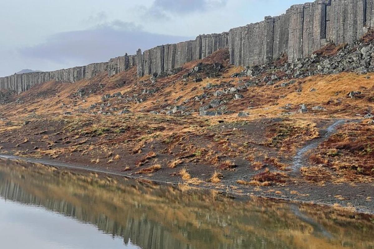 a fence on a hill next to a body of water