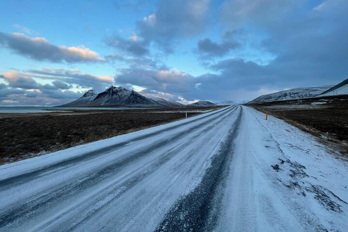 a snow covered road with a mountain in the distance