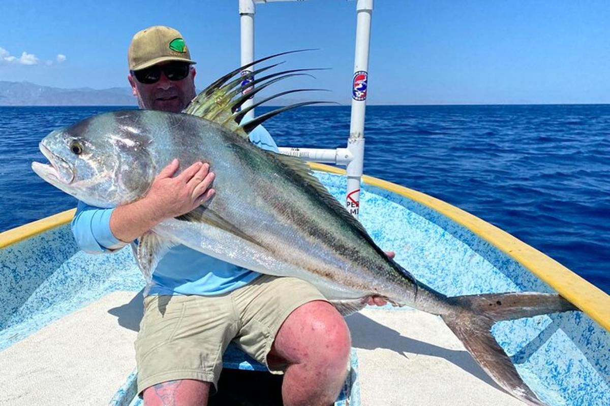 a man sitting on a boat holding a large fish