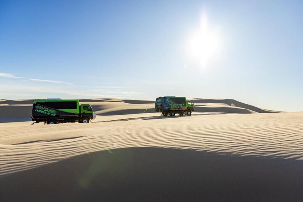 two trucks driving through the sand in the desert