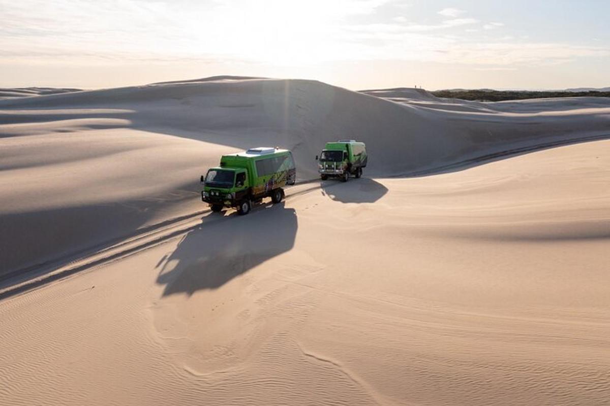 two trucks driving through the sand in the desert