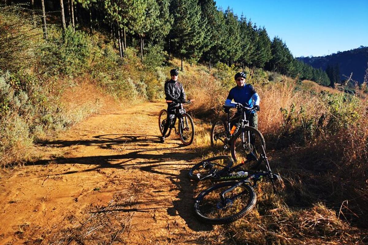 dvaja ľudia jazdiaci na bicykloch po prašnej ceste