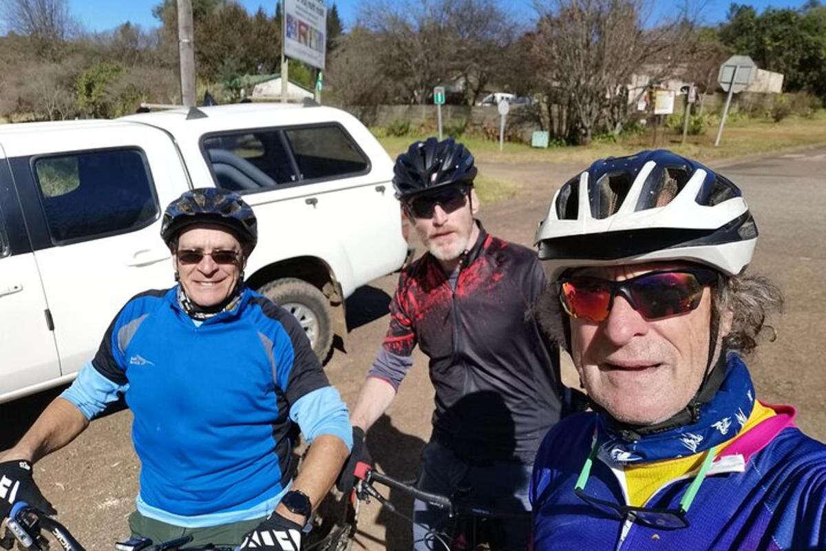 skupina troch ľudí na bicykloch pred autom