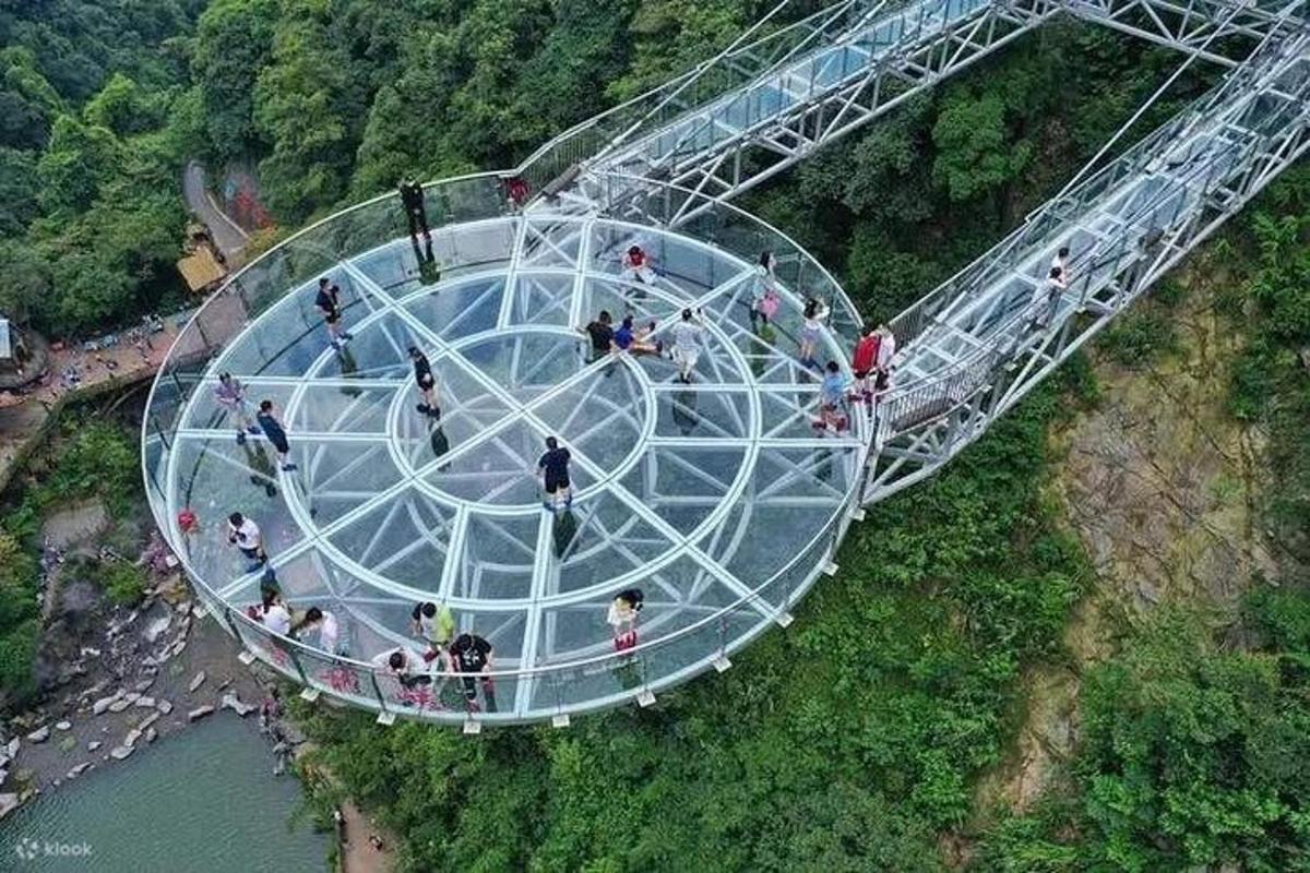 a group of people walking on a glass bridge over a river