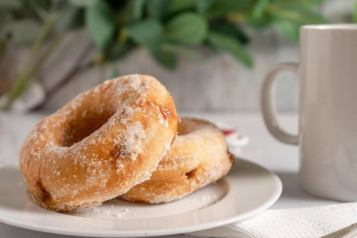 zwei Donuts auf einem Teller neben einer Tasse Kaffee
