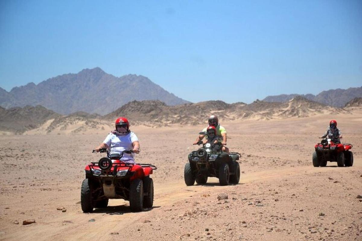 tre persone stanno guidando quad nel deserto