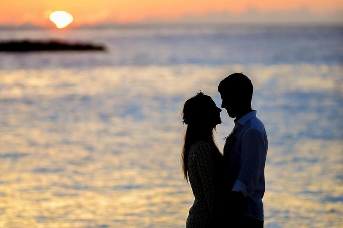 ein Mann und eine Frau stehen bei Sonnenuntergang am Strand