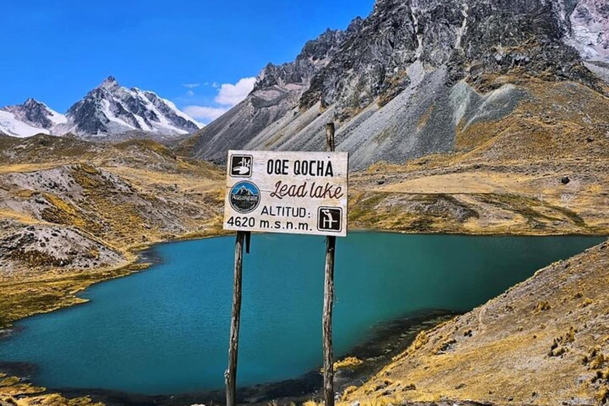 a sign in the middle of a mountain with a lake
