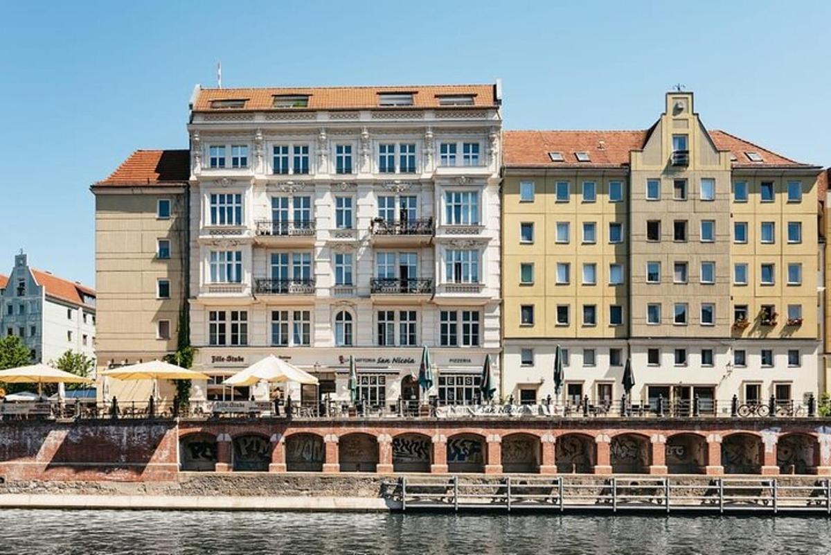 jõe ääres asuv hoone laudade ja päikesevarjudega