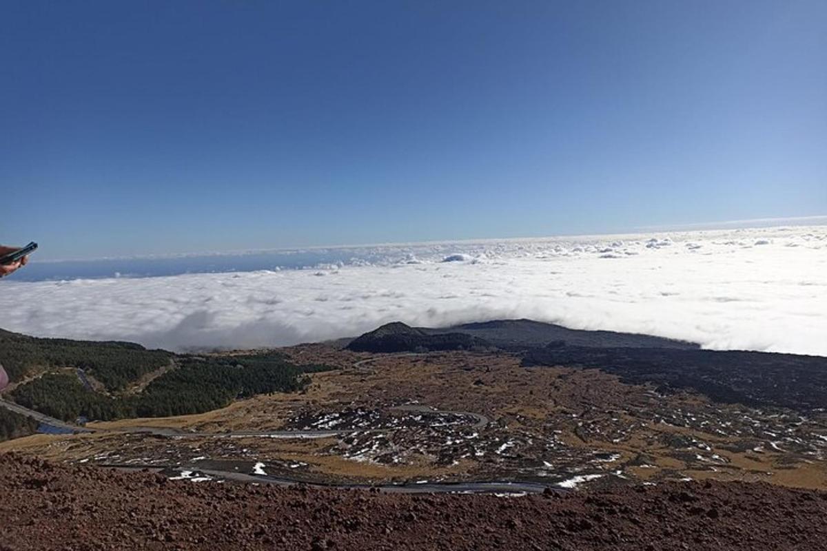 uma pessoa em pé no topo de uma montanha com nuvens