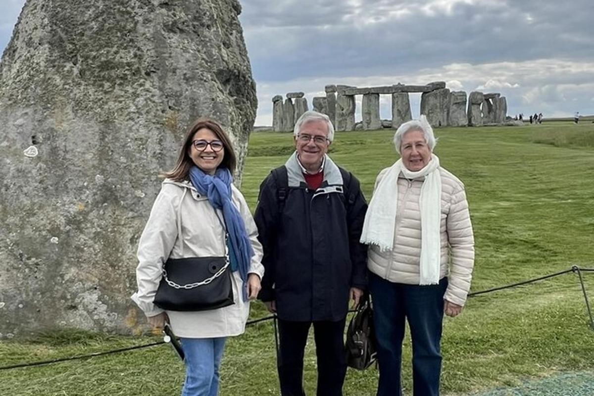 um grupo de três pessoas em pé em frente a Stonehenge