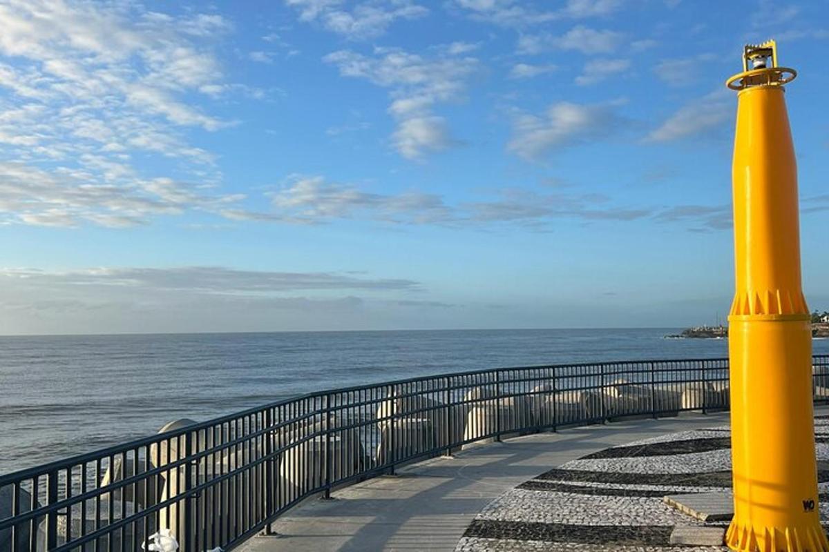 um poste amarelo em um calçadão próximo ao oceano