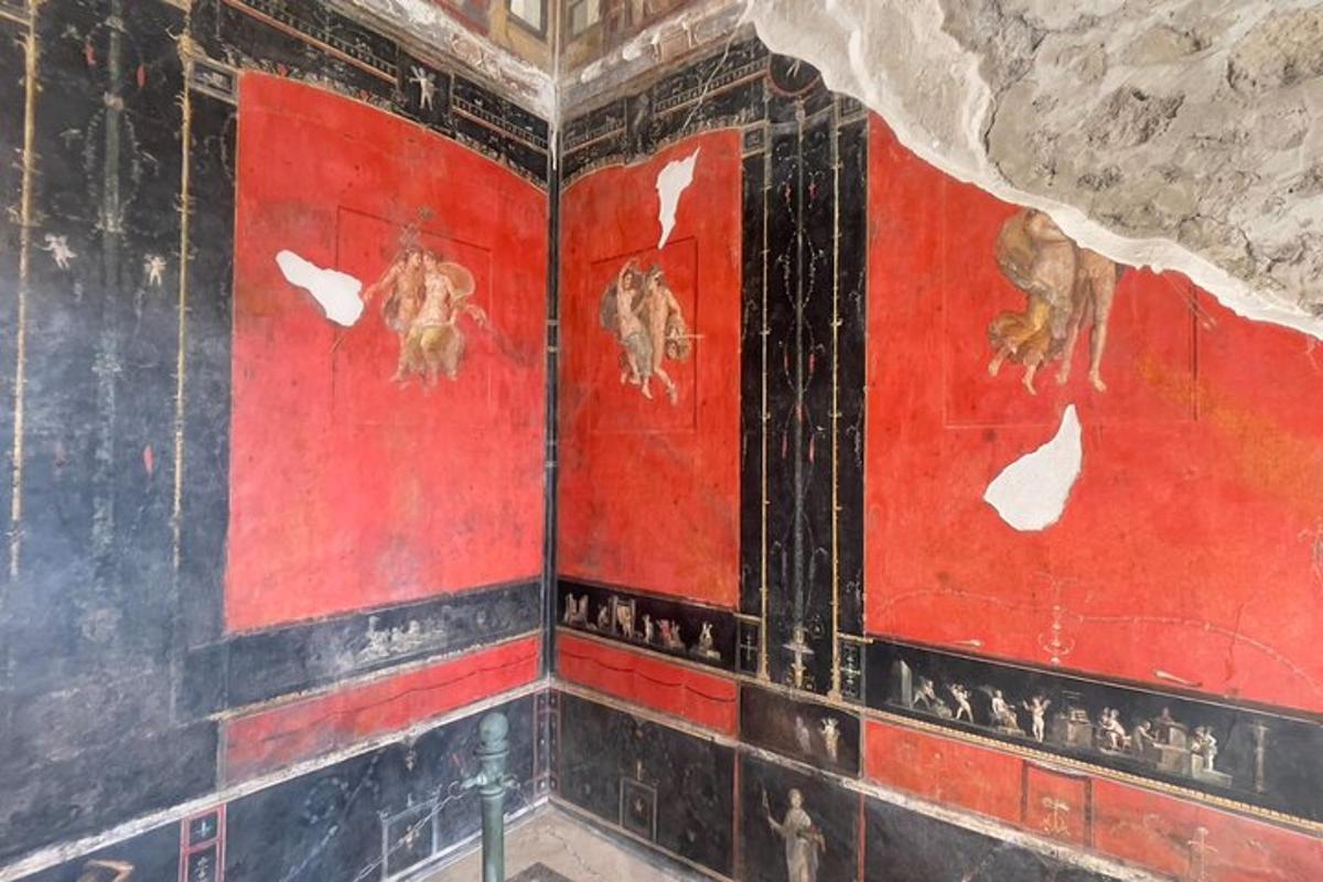 Una habitación con paredes rojas con pinturas.