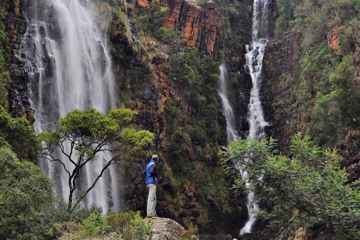 Ein Mann steht auf einem Felsen vor einem Wasserfall