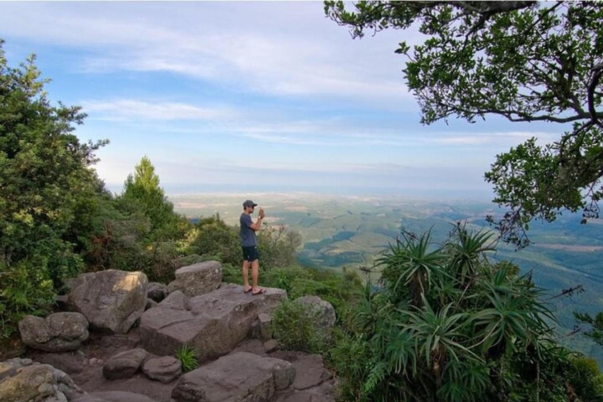 Ein Mann steht auf einem Berggipfel und macht ein Foto