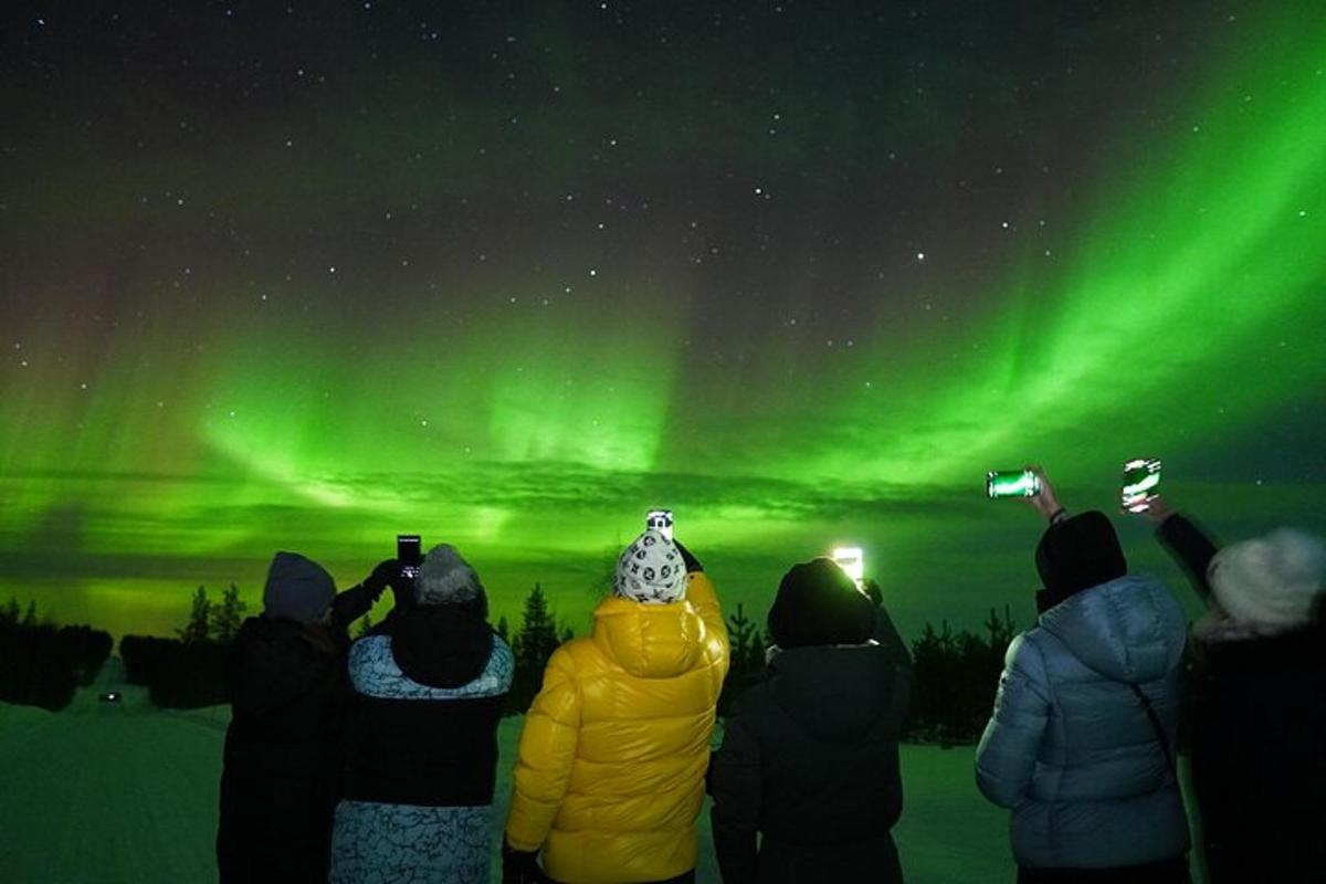 a group of people taking pictures of the northern lights