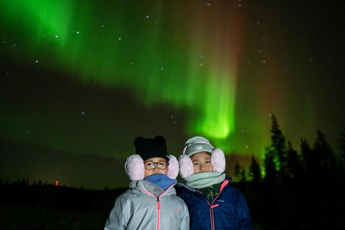 two people standing in front of the northern lights