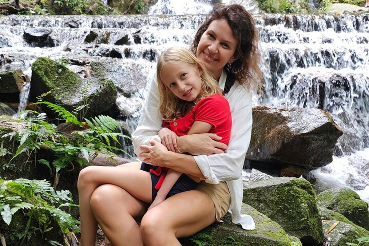 a woman and a little girl sitting in front of a waterfall