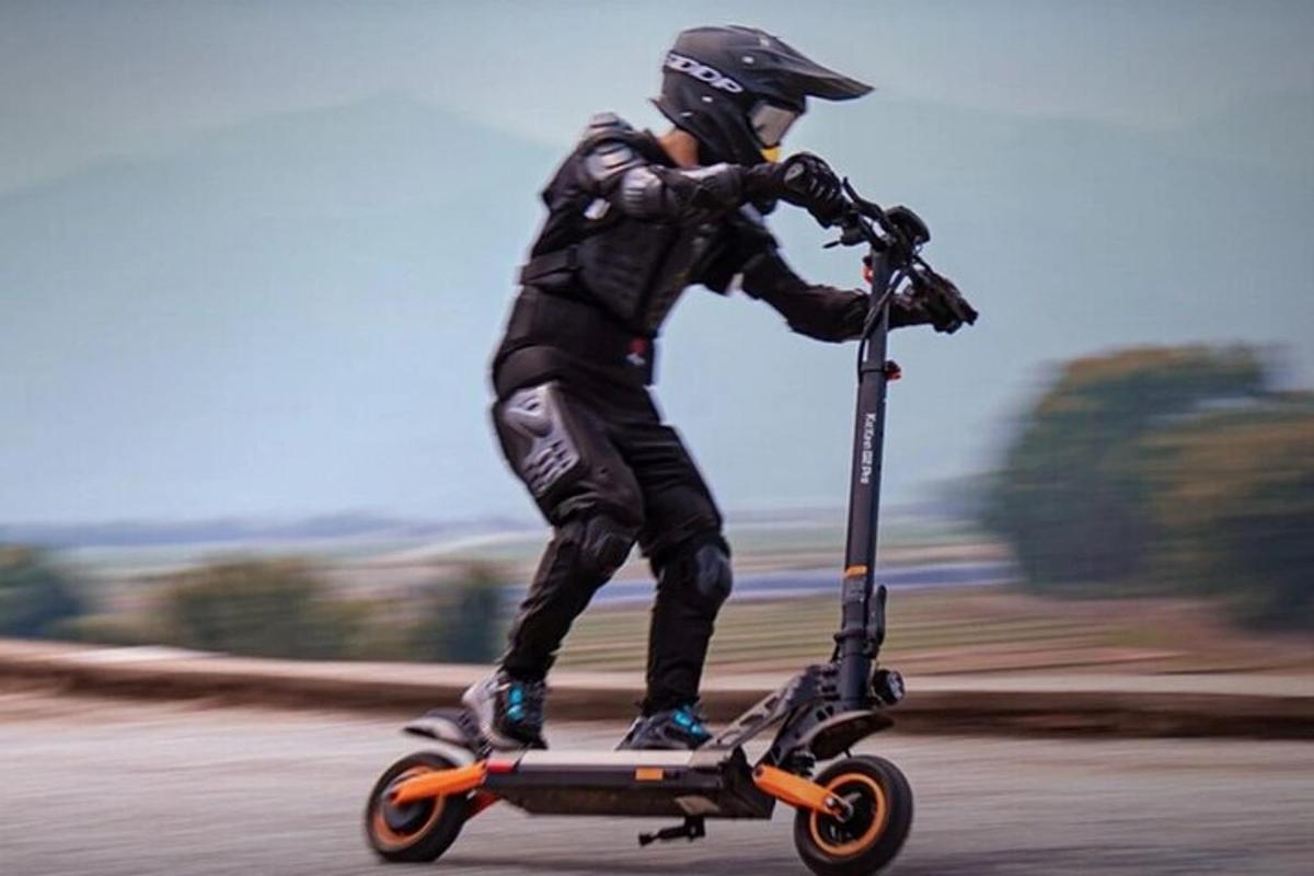 cilvēks brauc ar motorolleru pa ceļu