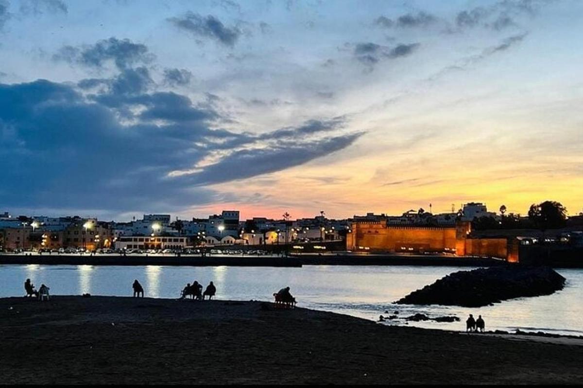 um grupo de pessoas andando a cavalo na praia ao pôr do sol