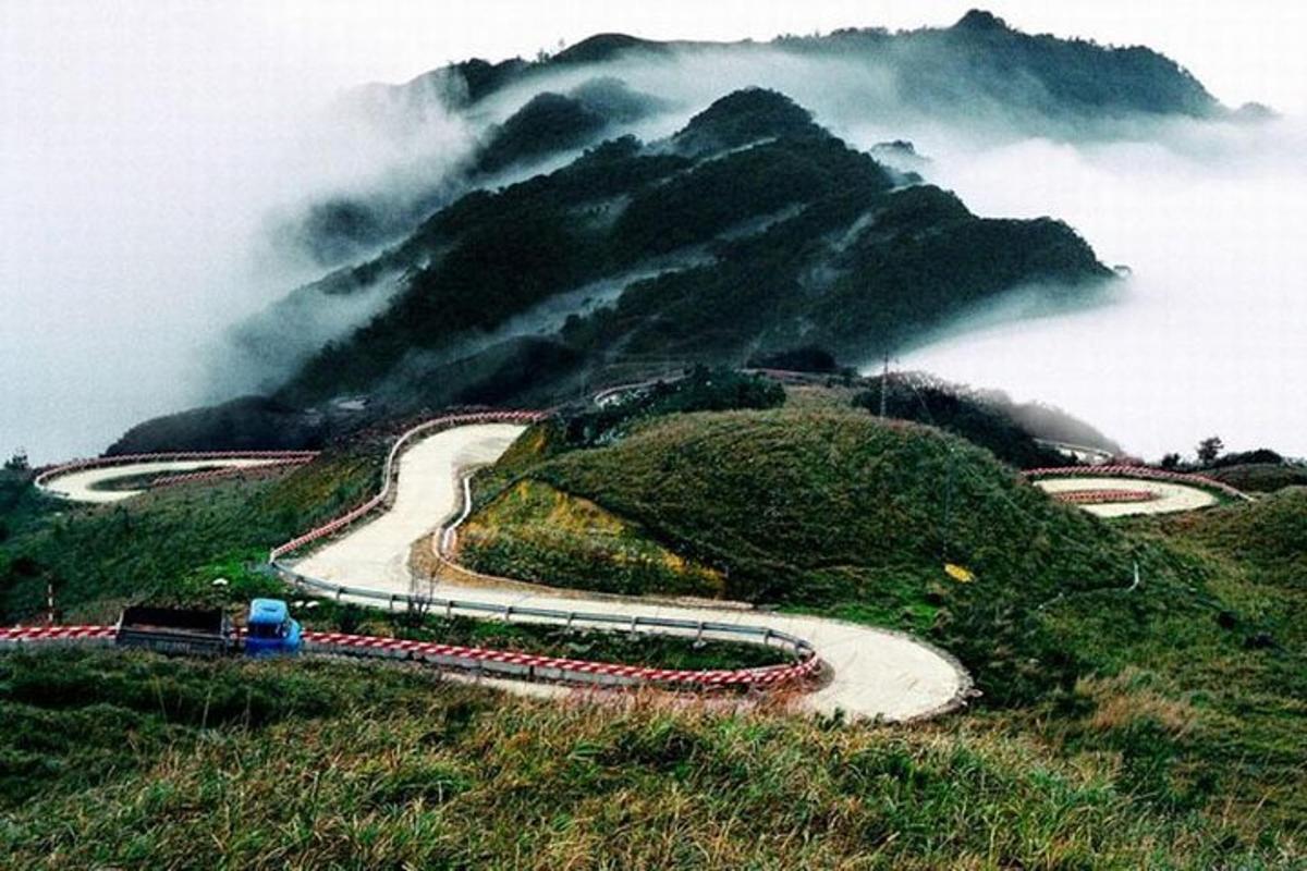 una strada tortuosa in cima a una montagna con nuvole