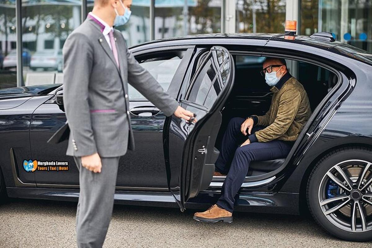 šalia automobilio stovintis vyras su kauke