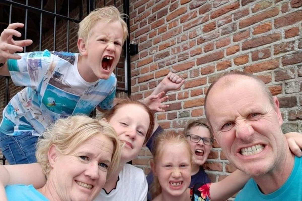 een groep mensen die naast een bakstenen muur staan