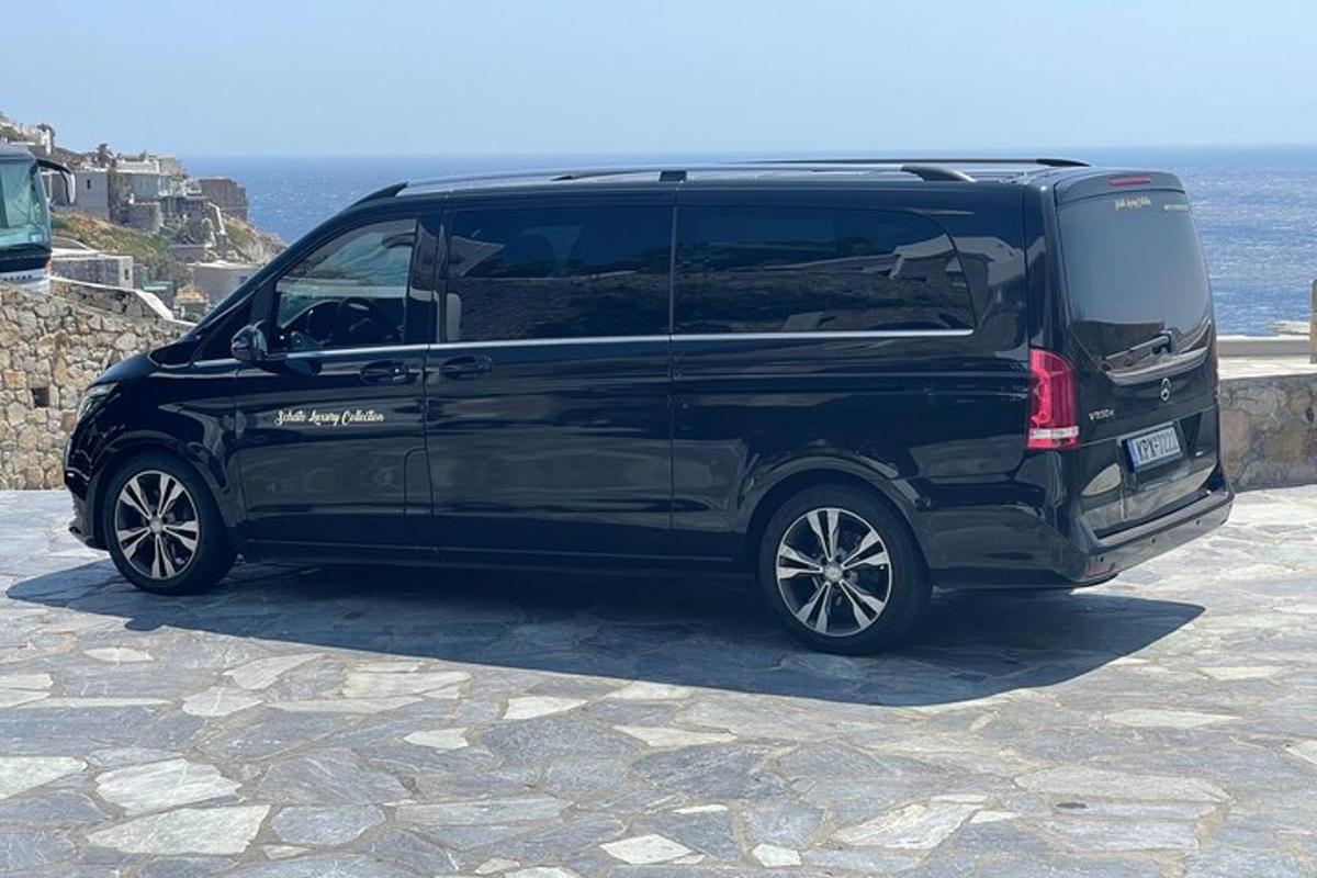 črn kombi parkiran na kamniti cesti ob oceanu