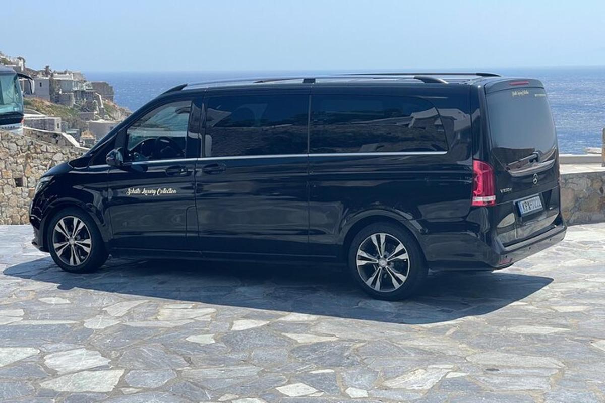 a black van parked on a stone road next to the ocean