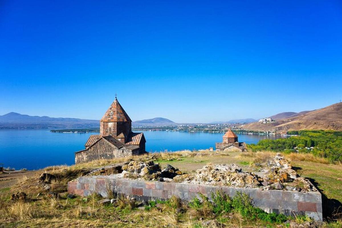 an old church on a hill next to a body of water