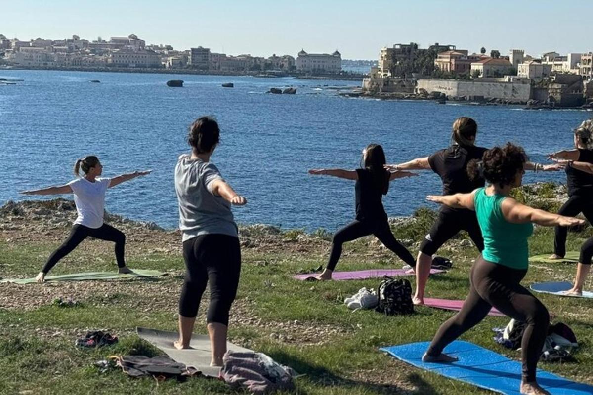 en gruppe mennesker som gjør yoga ved vannet