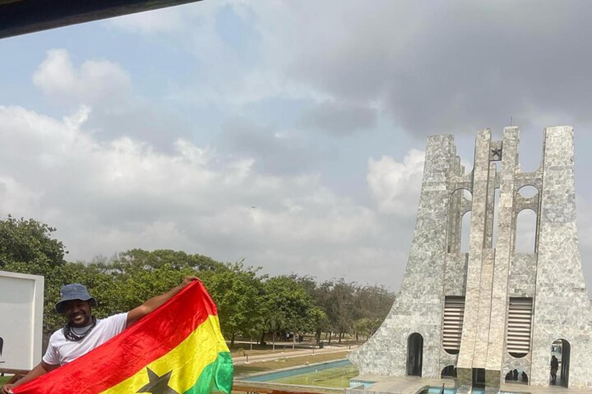 Un hombre sosteniendo una bandera frente a un monumento