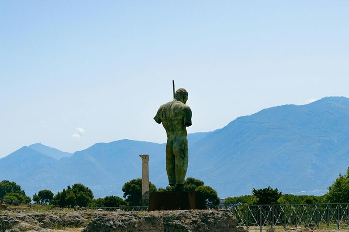 en statue af en mand, der står foran bjerge