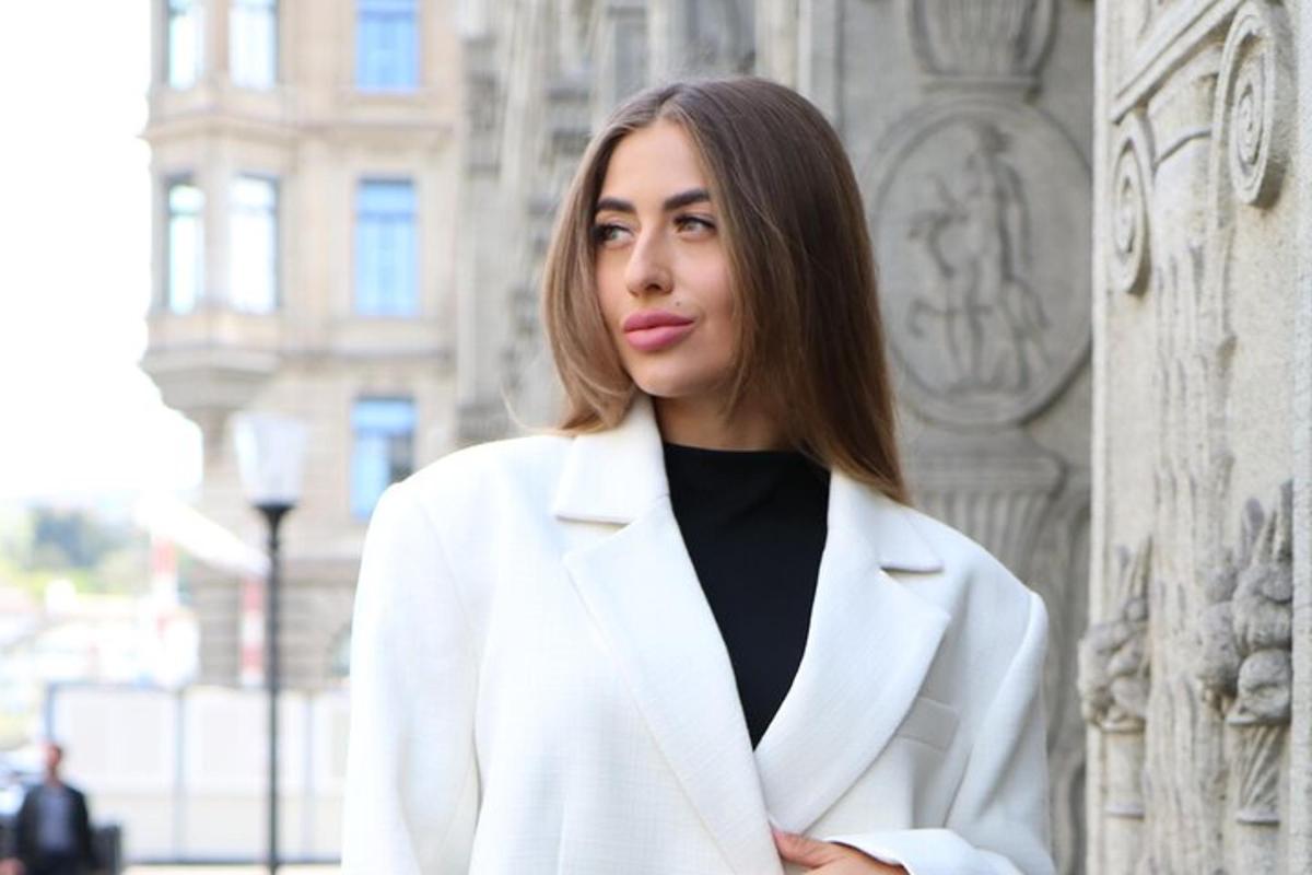 uma mulher de jaleco branco parada em frente a um prédio