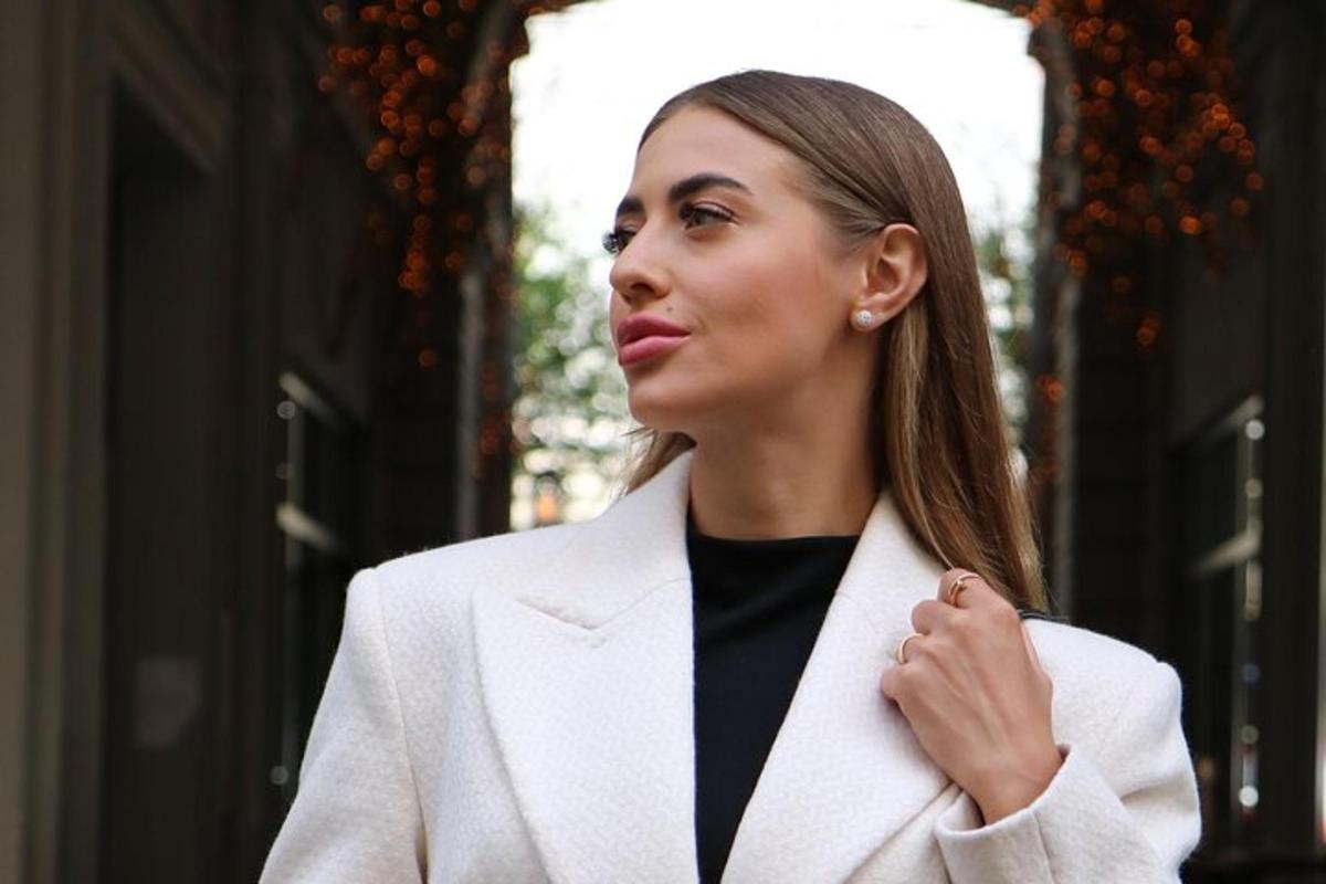 a woman in a white coat walking down a street