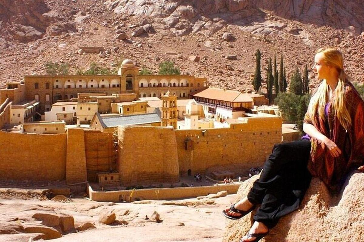 una donna seduta su una roccia che guarda una città