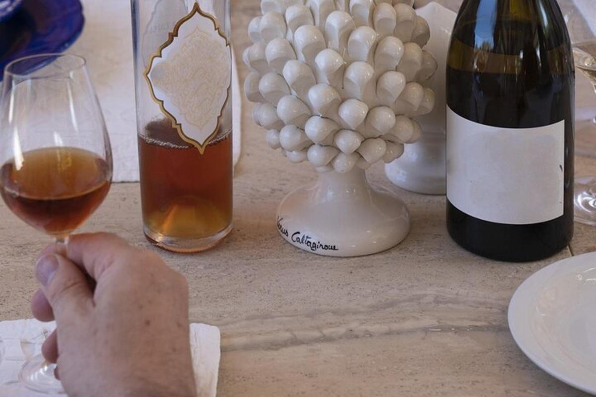 una persona sosteniendo una copa de vino junto a botellas de vino
