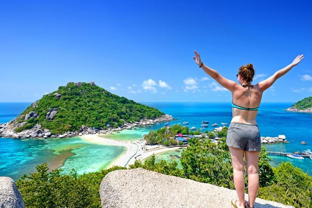 uma mulher em pé sobre uma rocha com vista para uma praia