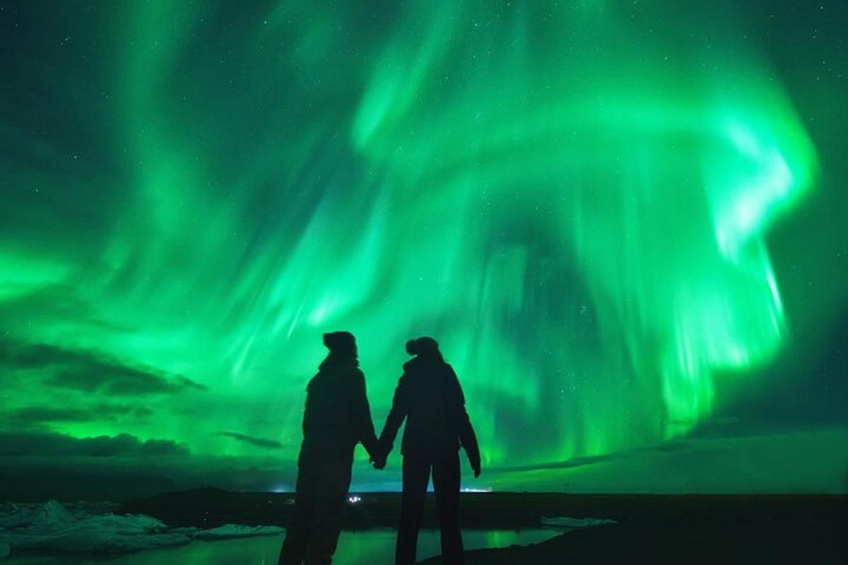 two people standing under the northern lights in the sky