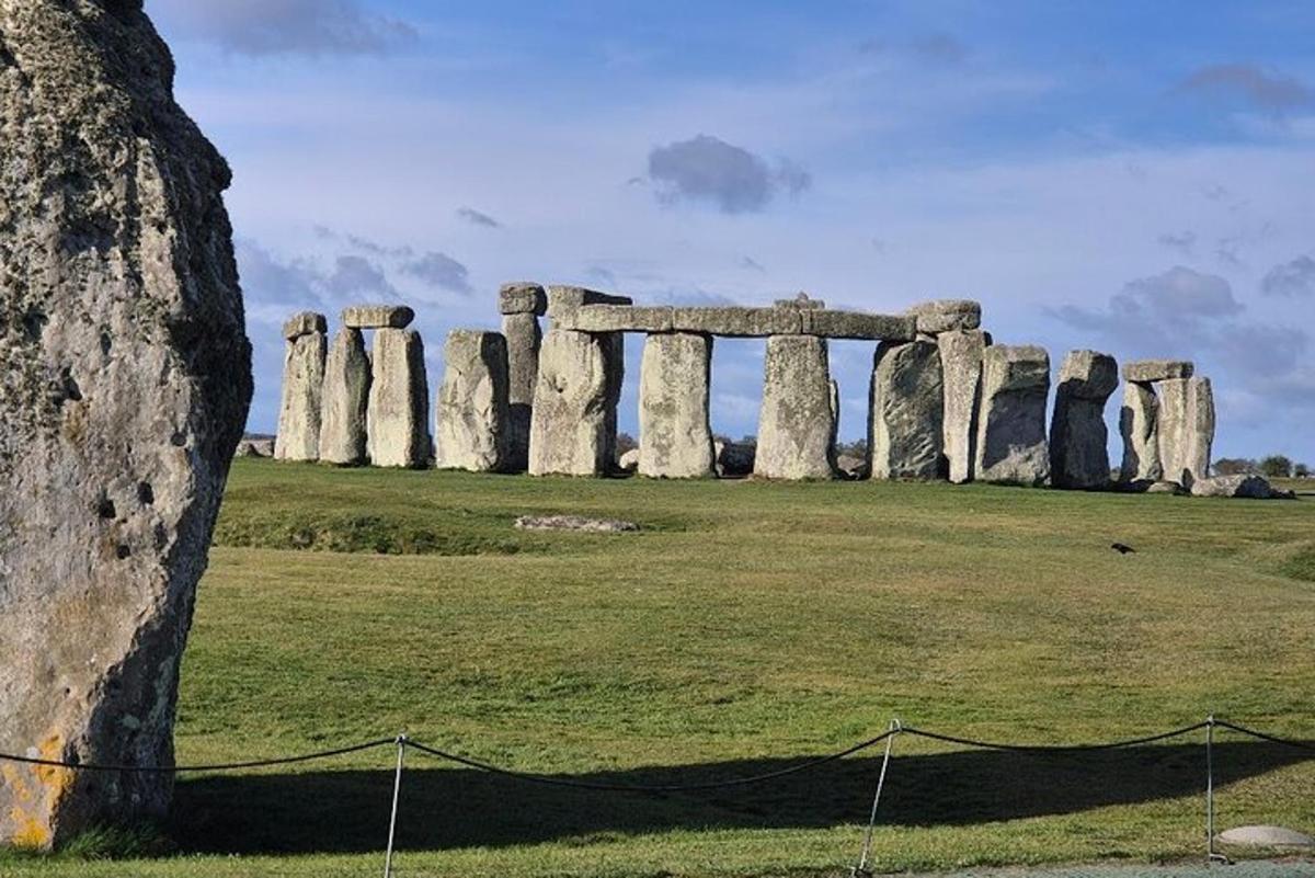 um antigo monumento de stonehenge em um campo com uma árvore